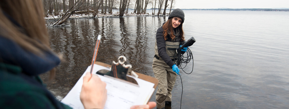 Two female appearing students testing water with equipment