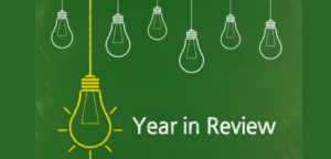 graphic image of small white lightbulbs and one larger lightbulb highlighting the text that says year in review on a green background