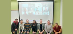 class photo of students in person and pictures on computer screens