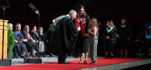 President Brule greeting graduate and daughter on convocation stage