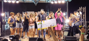 Jason Blaine on stage with others holding a large cheque