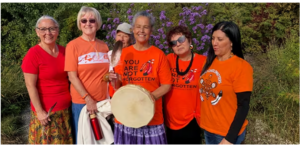 Pembroke campus marks National Day for Truth and Reconciliation. Five employees wearing orange shirts while Elder Aimee Biley holds a traditional drum