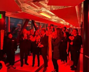 students celebrate ribbon cutting with Mayor Sutcliffe, Claude Brule and Lianne Laing in ARC pedestrian bridge, lit up red for Hearth Month