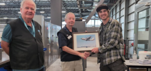 Peter Krayer and David Lowden present Brayden Krahn with a print of an airplane as a thank you gift.