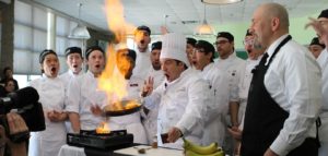 Chef with culinary students around fiery frying pan