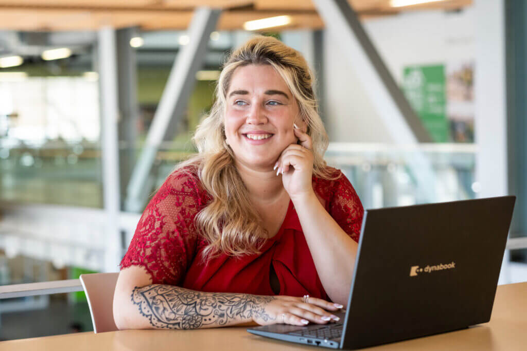 AC Online alumna Stephanie sits in front of a laptop with her face resting on her hand