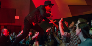 Singer interacting with audience during his concert under red lighting.