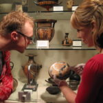 People examining an ancient bowl in front the've just removed from a glass case