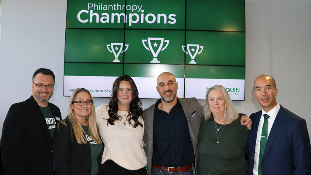 Six people stand in front of a sign that reads Philanthropy Champions.