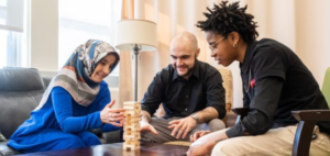 three people sitting around a table playing a block game and smiling at each other