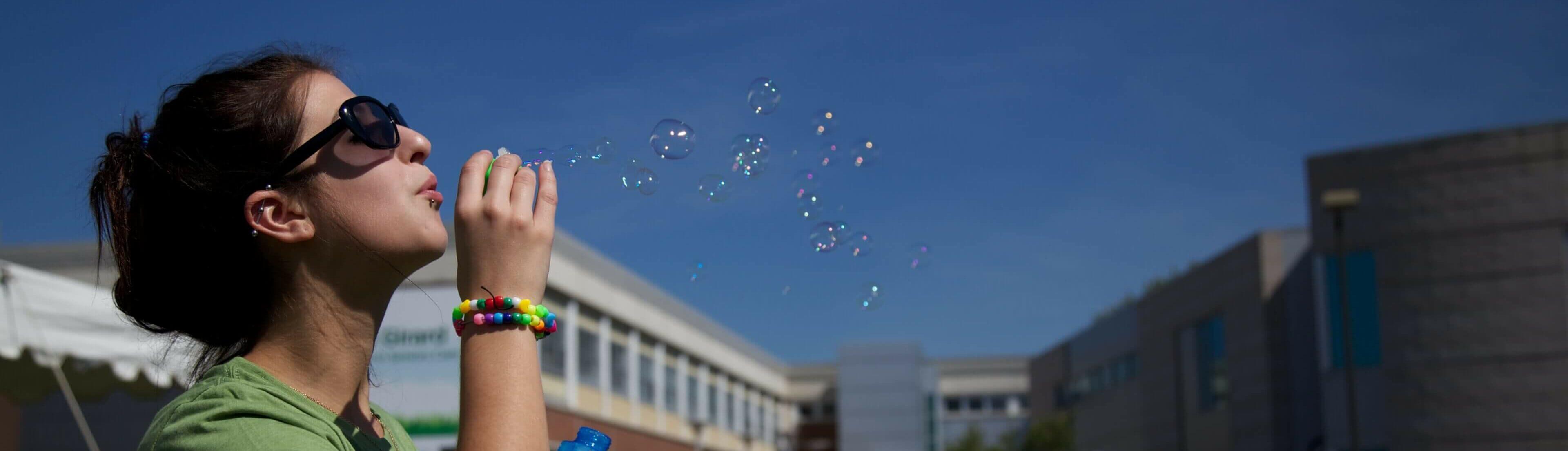 Student blowing bubbles in front of A Building at the Ottawa campus.