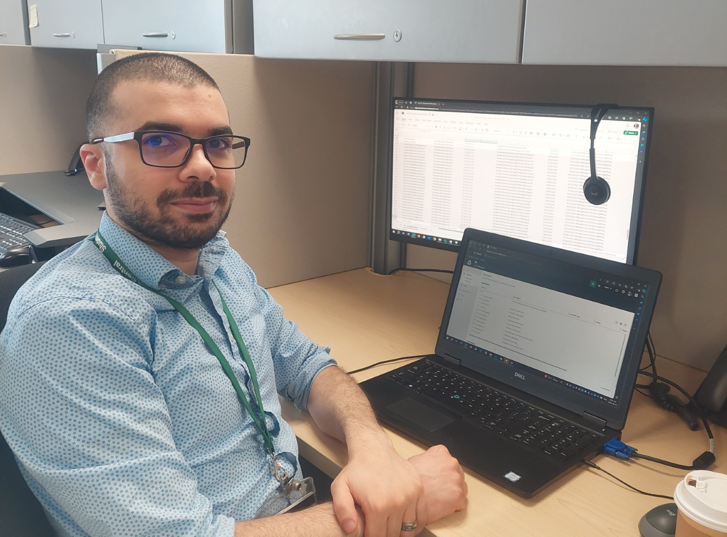 Michael Kahil sitting at his desk and smiling at the camera.