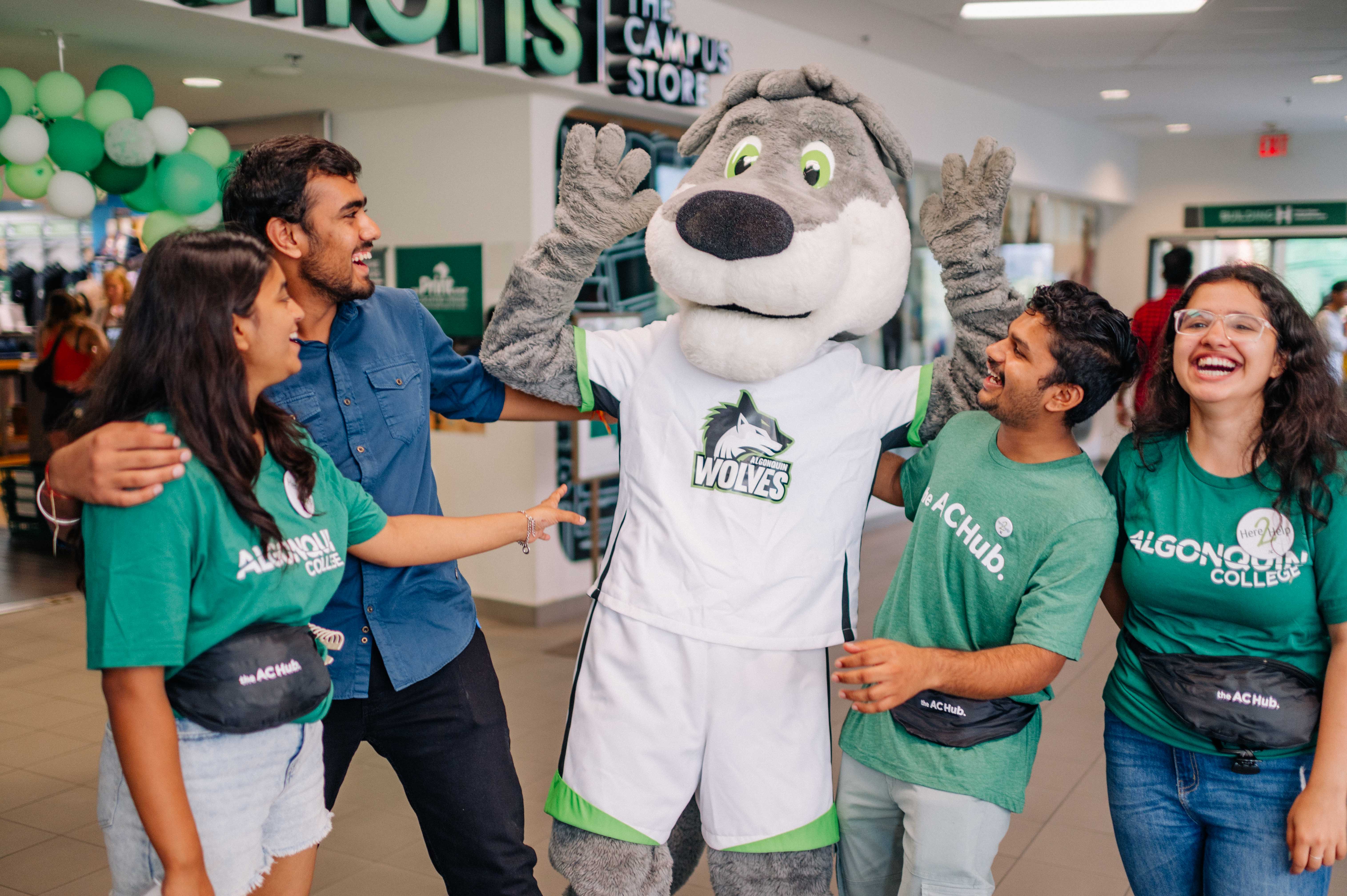 Thor, the mascot of Algonquin College Athletics, and four learners are smiling and hugging each other.