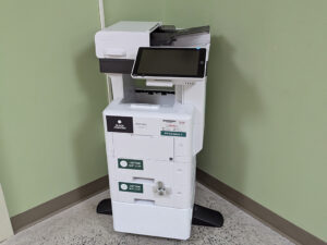 An image of a Ricoh multi function printer at the Perth campus located in the hall near room 112.