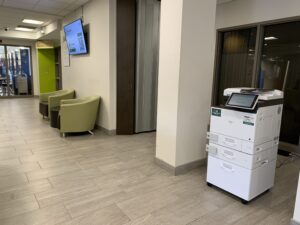 Image of a Ricoh multi-function printer in A building first floor hallway.