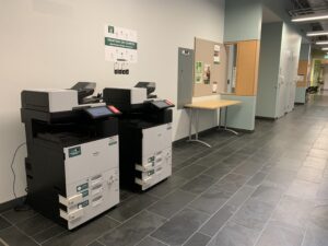 An image of two Ricoh multi function printers located on the third floor of ACCE building outside of room CA302.