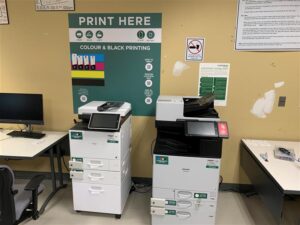 An image of two Ricoh multi function printer located on the second floor of T building in room T201 access lab.