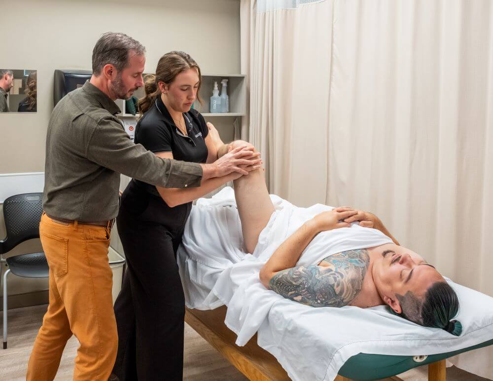 Professor demonstrating massage trigger points with a student